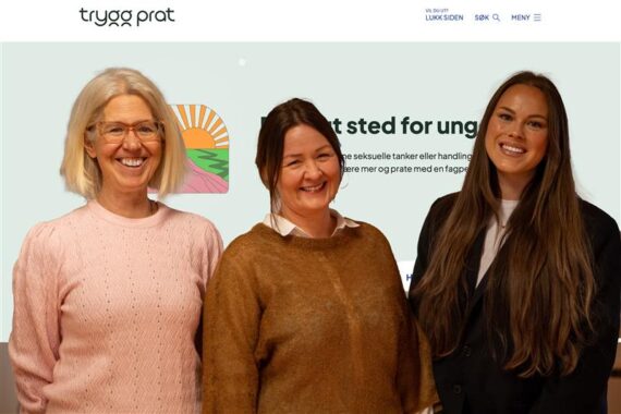 Tre kvinner står og smiler foran en skjerm som viser en nettside med logoen trygg prat og norsk tekst.