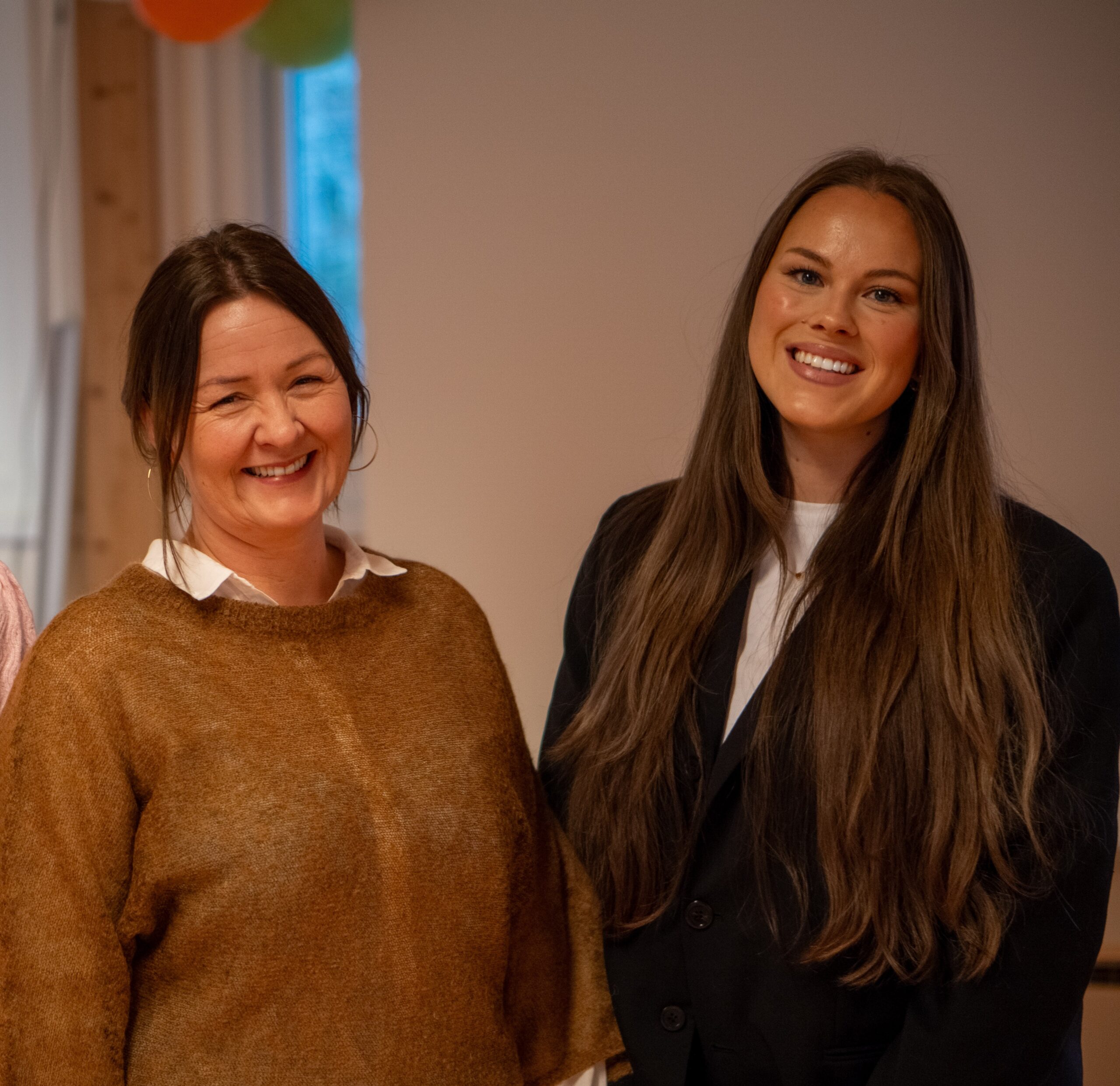 To kvinner står innendørs på Betanien sykehus og smiler til kameraet. Den ene har brun genser og hvit skjorte, den andre en svart blazer over en hvit topp. De representerer et lavterskeltilbud for å forebygge skadelig seksuell atferd.
