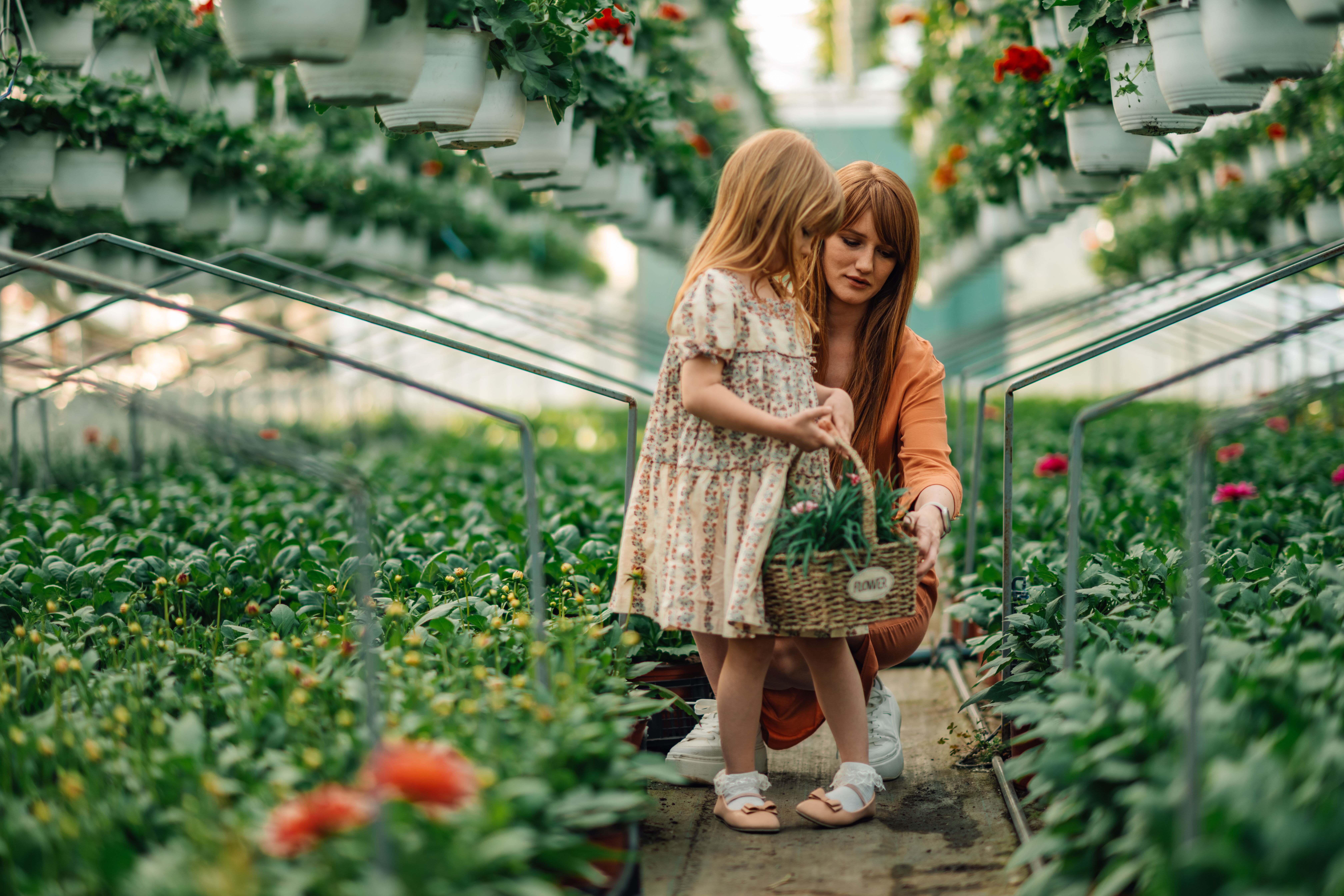 Mother and daughter florists with basket of flowers at greenhouse.