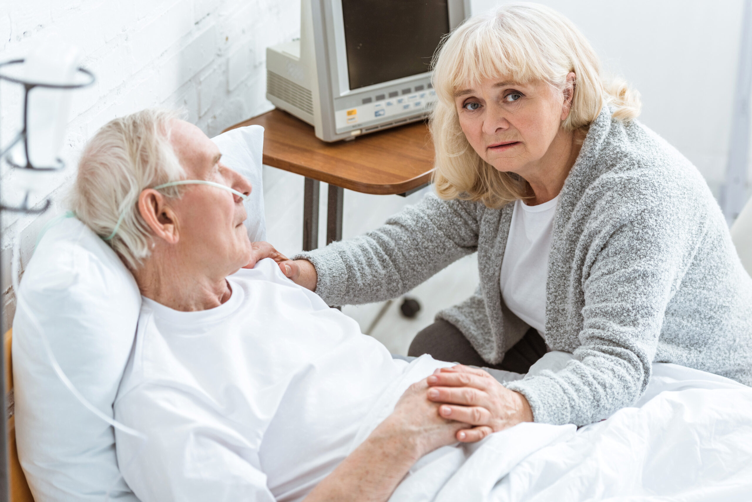 Sad senior woman with sick husband in hospital
